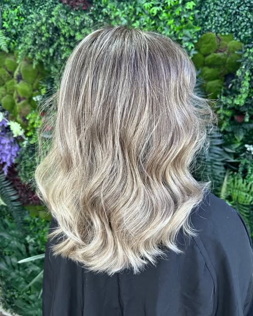 Bronde Balayage mit Wellen vor der Pflanzenwand
